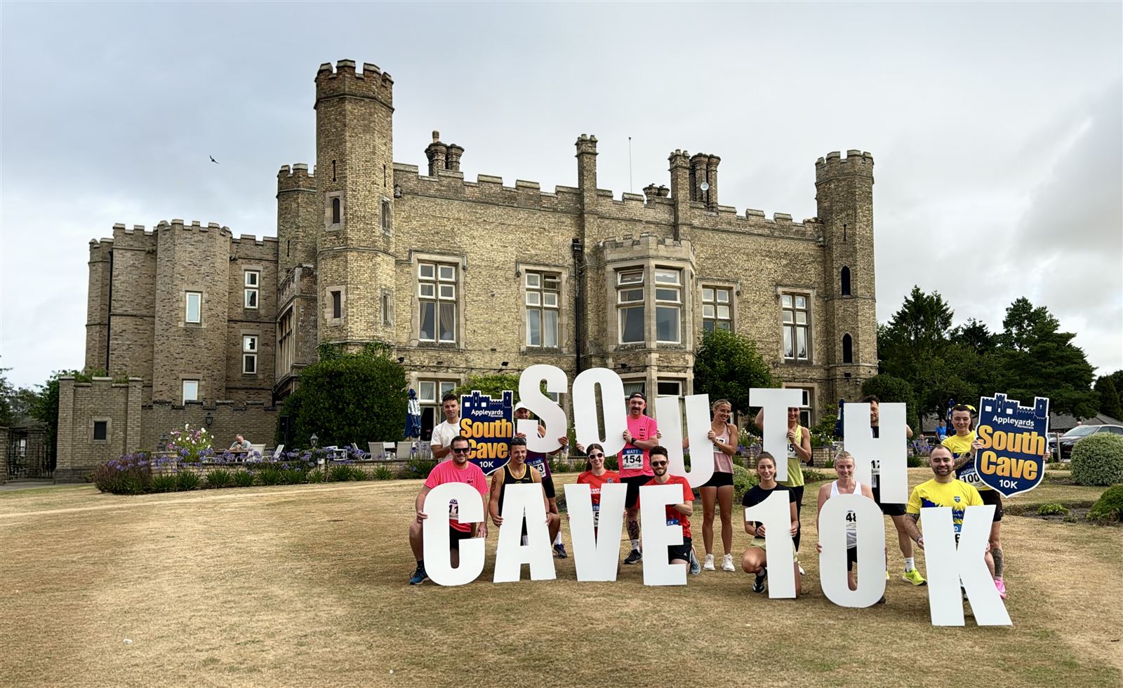 South Cave 10k runners holding giant SOUTH CAVE 10K letters in front of the castle