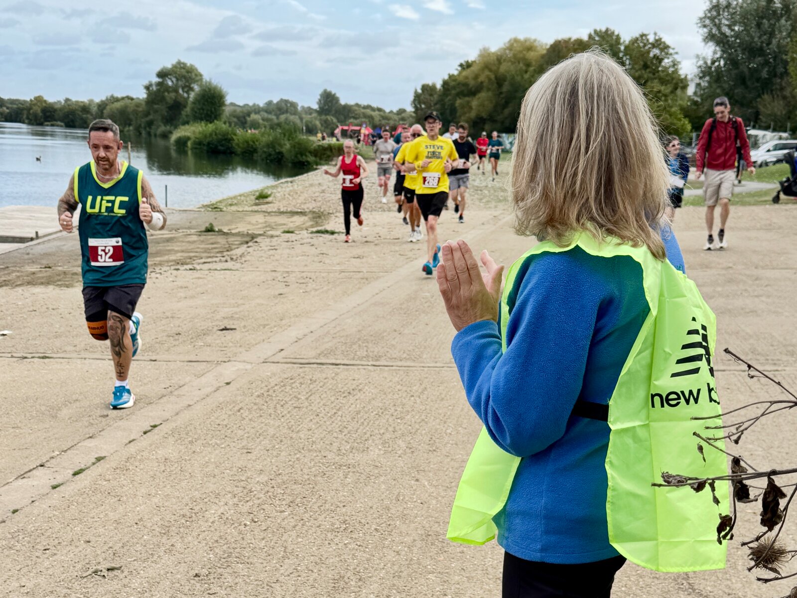 A marshal cheers on a runner beside the water at Thames 10k